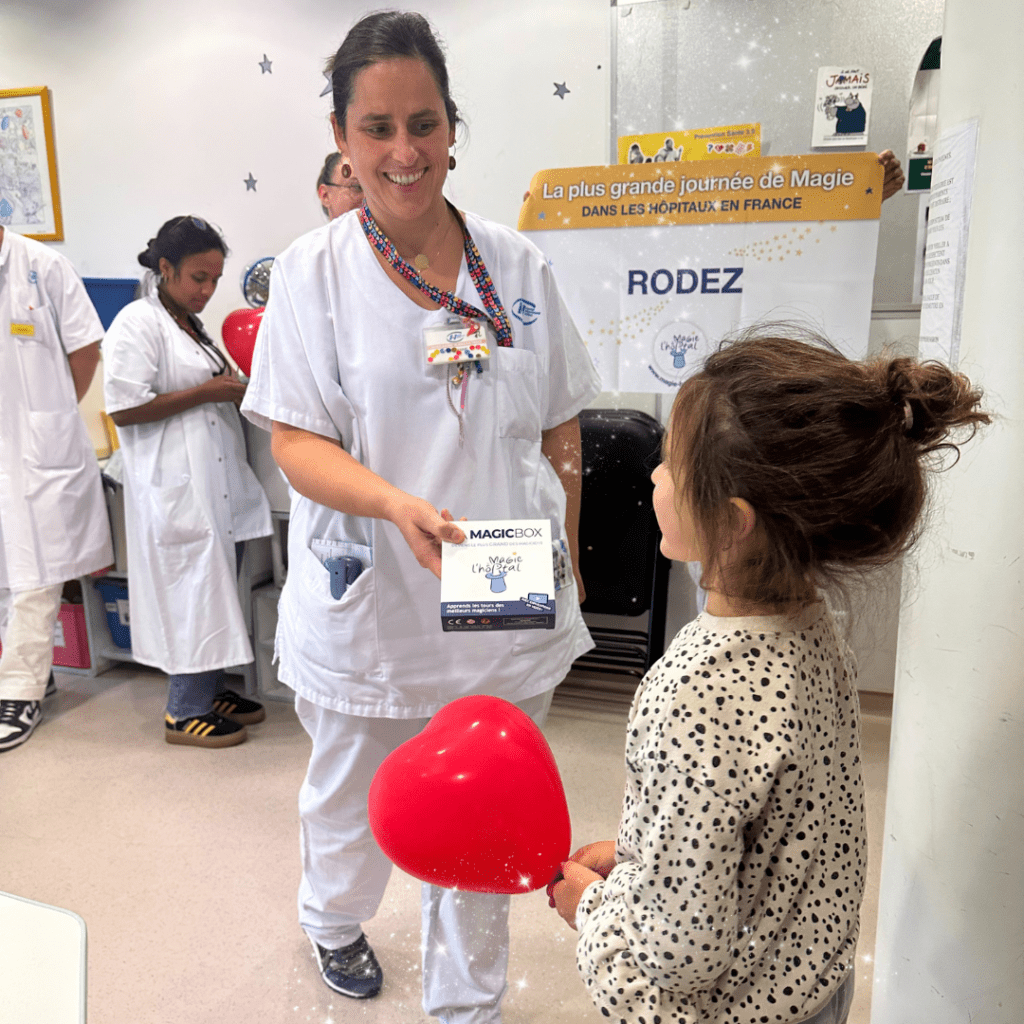 Une infirmière de l'équipe de pédiatrie donnant une boîte de magie à une enfant hospitalisée